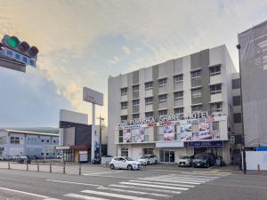Fukuoka Share Hotel في فوكوكا: مبنى كبير به سيارات تقف في موقف للسيارات