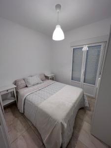 een witte slaapkamer met een bed en 2 ramen bij Sueña en la Plaza Cervantes 3 in Alcalá de Henares