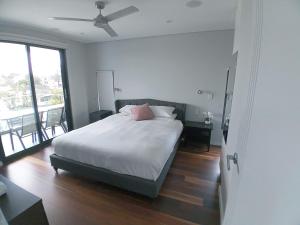 um quarto com uma cama com lençóis brancos e uma ventoinha de tecto em Brand NEW VIP Luxury 5/5 Star Beachside Escape em Sydney