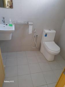 a white bathroom with a toilet and a sink at Cloud housing jabal shams in Sa‘ab Banī Khamīs