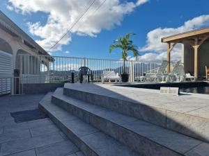 une terrasse avec des escaliers et des chaises ainsi qu'une piscine dans l'établissement Hébergements La Favorite, au Lamentin