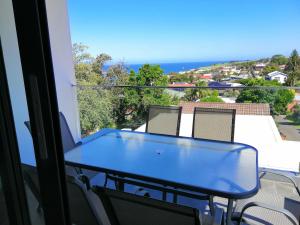 d'une table bleue et de chaises sur un balcon donnant sur l'océan. dans l'établissement Brand NEW VIP Luxury 5/5 Star Beachside Escape, à Sydney