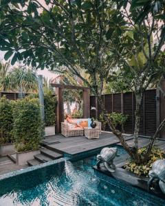 einen Hinterhof mit Pool mit Sofa und Baum in der Unterkunft Anantara Mai Khao Phuket Villas in Mai Khao Beach