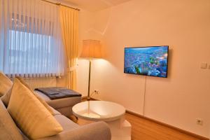 a living room with a couch and a tv on the wall at Heimat Goslar Apartments "Zum Marktplatz" in Goslar