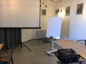 een wit scherm in een kamer met een tafel en een podium bij Hôtel Océan Dinan in Dinan