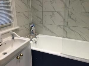 a bathroom with a white tub and a sink at TDM Bachelot Lettings Ltd in London