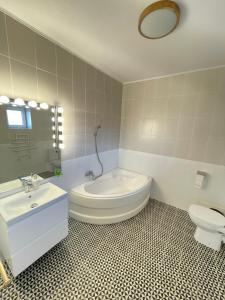 a bathroom with a tub and a toilet and a sink at BioLocalia House Bucovina in Baloteşti