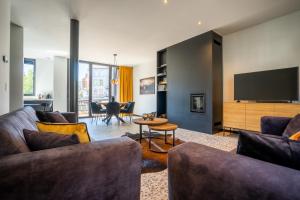 a living room with a couch and a tv at La Maison Noire in La Roche-en-Ardenne