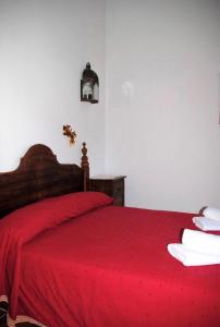een slaapkamer met een rood bed en een rode deken bij Casa Muñecas in Montejaque