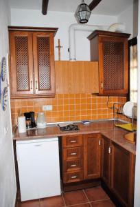 cocina con armarios de madera y nevera blanca en Casa Muñecas en Montejaque