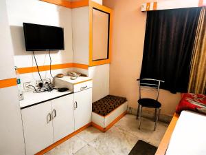 Habitación pequeña con TV y silla en STAYMAKER Tirupati Guest House, en kolkata