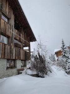 a house covered in snow in front of a building at Mountain Home Villa Anna in Selva di Val Gardena