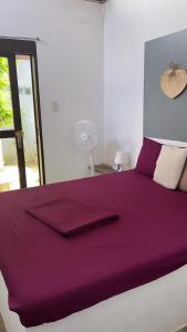 a bedroom with a purple bed with a window at Yay Lodge SIARGAO, private room 2 with AC & hot shower and fast Starlink Wifi in General Luna