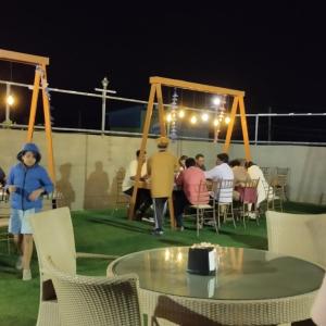 een groep mensen die 's nachts rond een tafel zitten bij Mannat Inn TS Mysore - Premium Homestay in Mysore