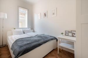 a white bedroom with a bed and a window at Liget Apartment in Budapest