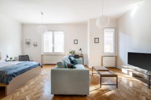 een slaapkamer met een bed, een bank en een tv bij Liget Apartment in Boedapest