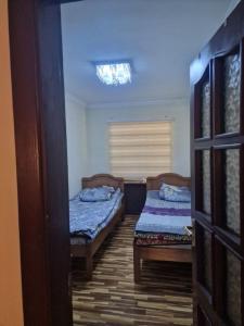 een kamer met 2 bedden en een deur naar een slaapkamer bij Buz-2 in Yalanghoch