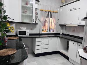 a kitchen with white cabinets and a microwave at Alojamientos María 1 in Seville