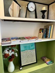 a shelf with a clock and books and a vase at Swing & Pillows @ Muntri in George Town