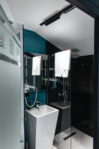 La salle de bains est pourvue d'un lavabo blanc et d'une douche. dans l'établissement Aratta Boutique Hotel, à Erevan