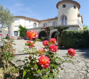 une maison avec des roses rouges devant elle dans l'établissement le relais fleuri, à Alès