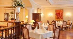 ein Restaurant mit Tischen und Stühlen in einem Zimmer in der Unterkunft Victor's Residenz-Hotel Erfurt in Erfurt