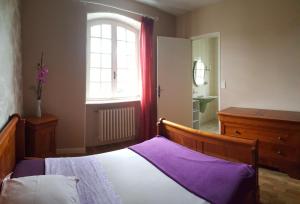 ein Schlafzimmer mit einem Bett mit violetter Bettwäsche und einem Fenster in der Unterkunft le relais fleuri in Alès