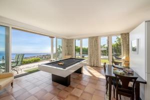 sala de estar con mesa de billar y ventanas grandes en Villa Rostrum by Villa Plus, en Funchal