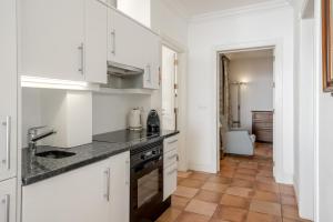 una cocina con armarios blancos y fregadero en Villa Rostrum by Villa Plus, en Funchal