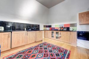 a large kitchen with wooden cabinets and a rug at 3-Bedroom Penthouse, Brentford, Free Parking in Brentford