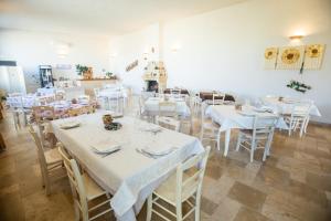 une salle à manger avec des tables et des chaises blanches dans l'établissement Agriturismo "Il Vignale", à Ostuni