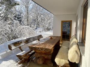 a room with a wooden bench and snow covered trees at Ferienwohnung Waldgarten in Leiten