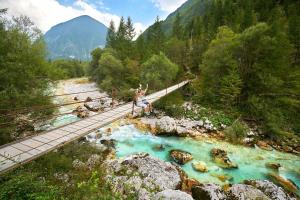 a woman sitting on a suspension bridge over a river at Bovec Garni Apartment 7 in Bovec
