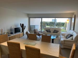 una sala de estar con un sofá, una mesa y sillas en Le Refuge Présidentiel : Charme et Commodités, en Le Touquet-Paris-Plage