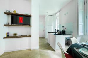 eine weiße Küche mit einem TV an der Wand und einem Waschbecken in der Unterkunft HL Apartment - Sant'Ambrogio, Duomo in Mailand