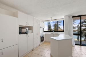 eine Küche mit weißen Schränken und einem großen Fenster in der Unterkunft Allamanda, Unit 11, 32 Esplanade, Bulcock Beach in Caloundra