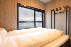 a bedroom with a large window with a view of the water at Luksus panorama hytte -H24 in Mestervik