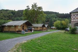 a row of lodges on a road next to a house at Camping Village Sy in Ferrières