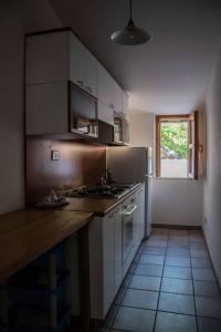 una cucina con armadi bianchi, lavandino e finestra di Chiaro di Luna - Appartamento vista mare a Pisciotta