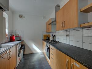 a kitchen with wooden cabinets and a black counter top at Pass the Keys Colourful property sleeps 6 in Manchester