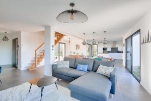 ein Wohnzimmer mit einem blauen Sofa und einer Küche in der Unterkunft Ambiance detente, piscine et vue mer in Pléneuf-Val-André