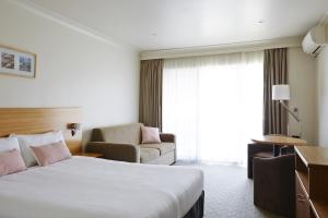 ein Hotelzimmer mit einem Bett und einem Stuhl in der Unterkunft Bay Beach Motel in Byron Bay