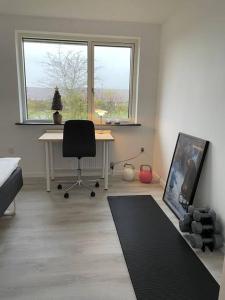 Skønt rækkehus med have في Gistrup: غرفة بها مكتب وطاولة وكرسي