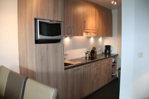 a kitchen with wooden cabinets and a tv on the wall at Zouterik 33* in Nieuwvliet