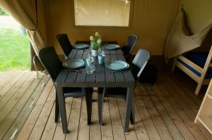 a table in a tent with chairs and plates on it at Camping Village Sy in Ferrières