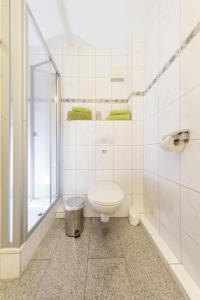 a white bathroom with a toilet and a shower at Marbijes Appartementhaus in Cuxhaven