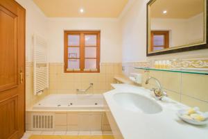 bagno con vasca, lavandino e specchio di Hotel AlpenSchlössl a Sankt Johann im Pongau