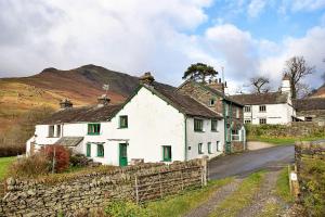 a white house with green windows and a stone wall at Finest Retreats - No 2 Town Head Cottages in Grasmere
