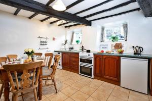 una cocina con armarios de madera, mesa y sillas en Finest Retreats - No 2 Town Head Cottages, en Grasmere