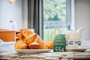 a plate of croissants and bread on a bed at Hôtel Compostelle in Lourdes